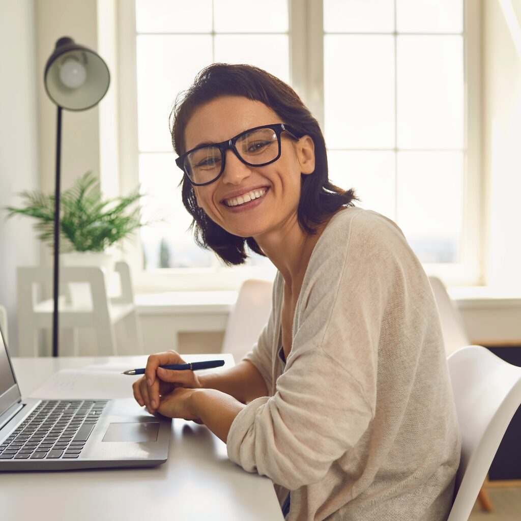 A woman smiling at a laptop after getting digital support.